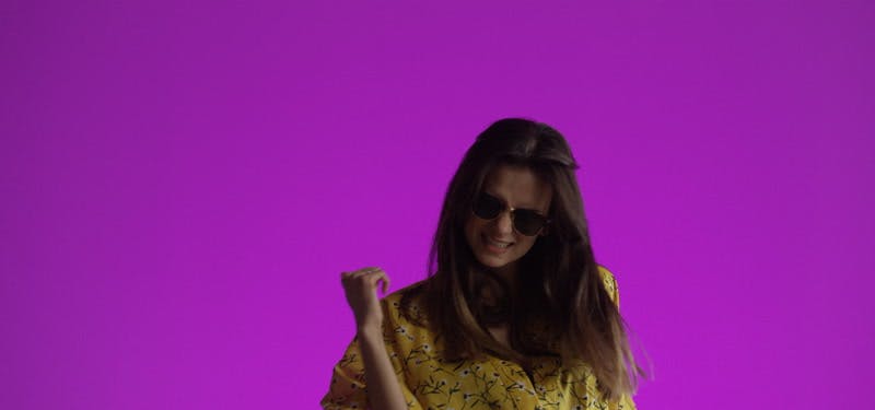model clicking her fingers while wearing sunglasses in purple background