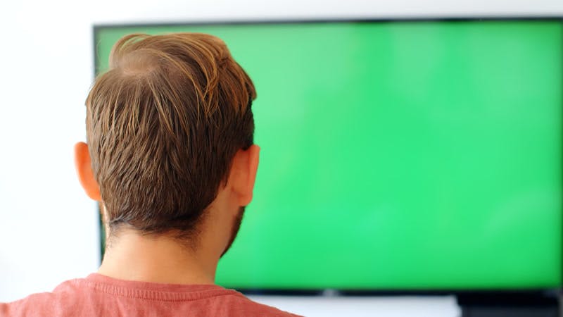 man cheering while watching a television green screen