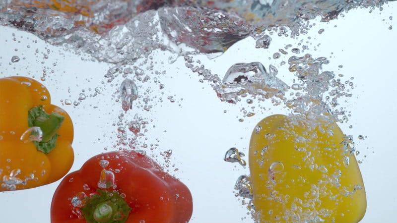 red orange and yellow peppers submerging in water