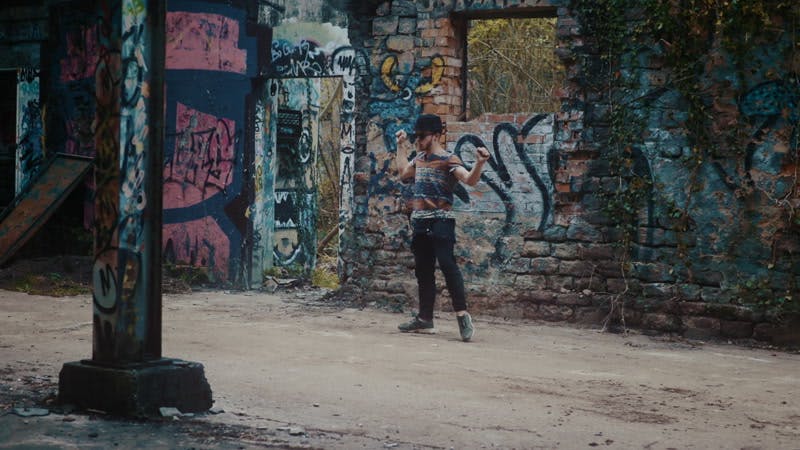 man dancing in front of graffiti on wall in abandoned building