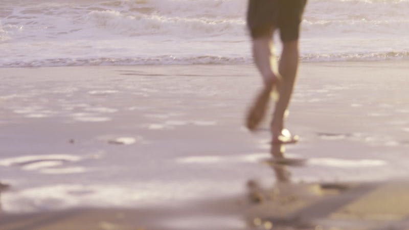 group of people laughing and running into breaking waves on a beach