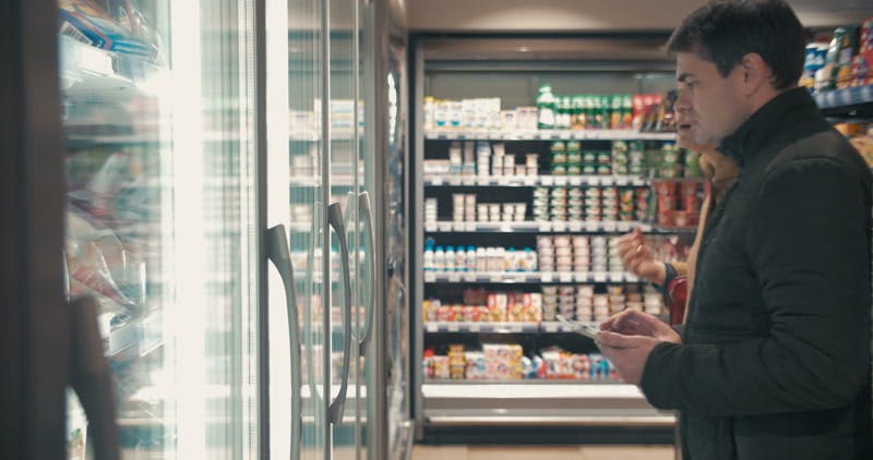 couple taking food from the fridge in the supermarket