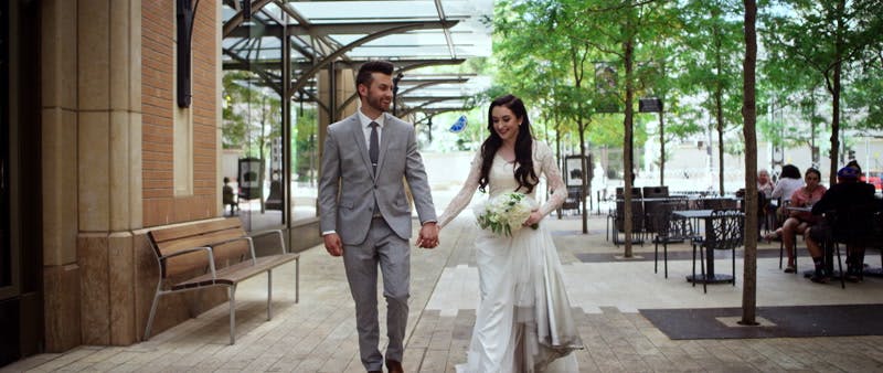 bride and groom walking around while holding hands