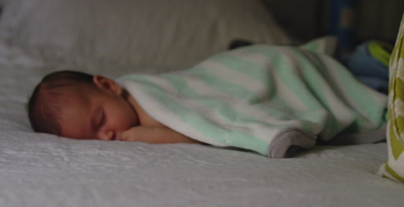 peaceful baby covered with soft blanket sleeping on bed 