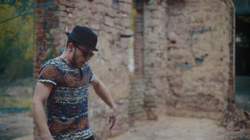 man with black hat dancing in abandoned brick building 