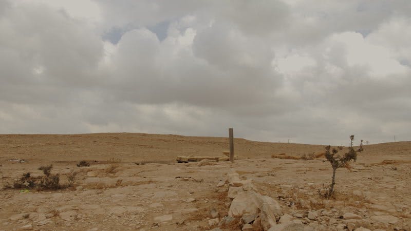 wooden pole in ground in desert on cloudy day