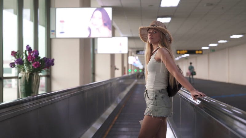 A woman walking briskly through an airport corridor with a suitcase