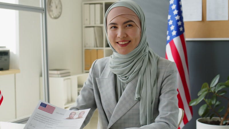 An immigration officer at a desk reviewing a U.S. passport application