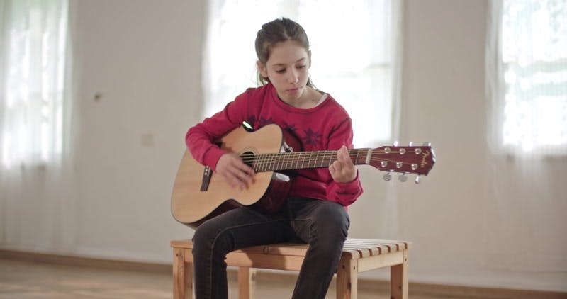 girl playing chords on the guitar and singing