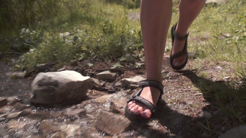 Woman in sandals crossing a narrow stream