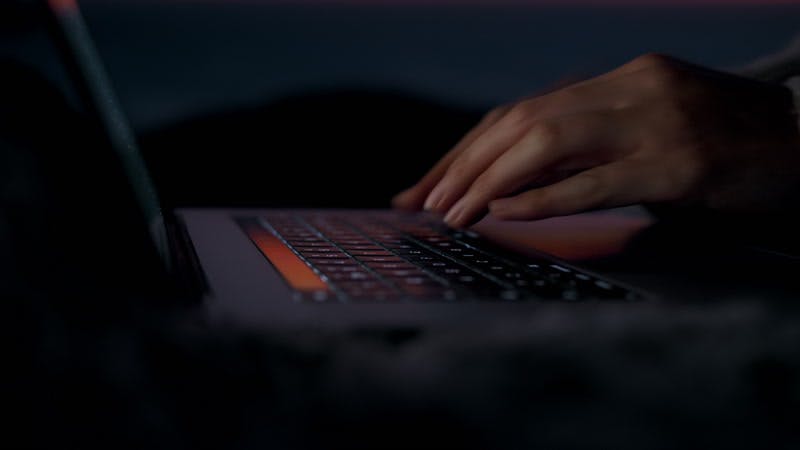 woman typing on a laptop outdoors at sunset