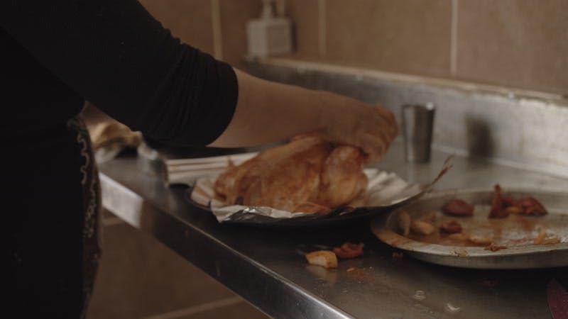 woman wraps spiced raw chicken in foil in kitchen