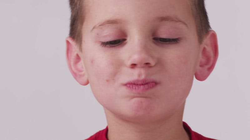 little boy chewing food and putting kiwi slices over his eyes