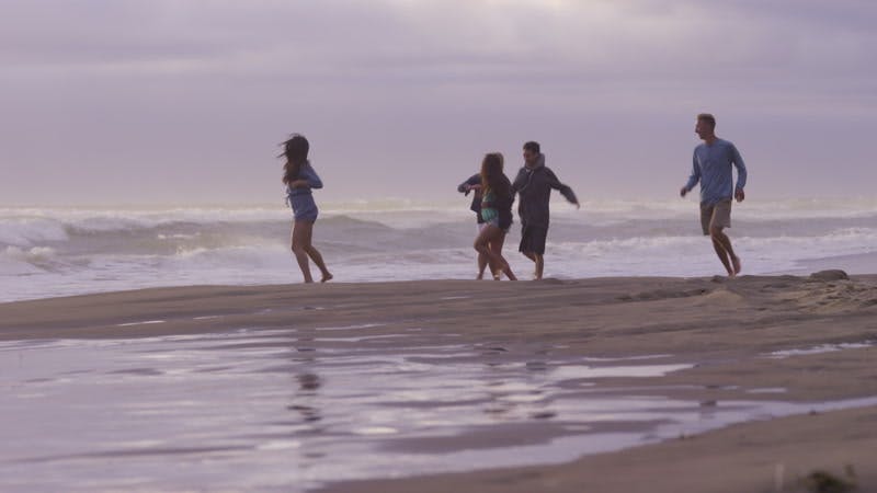 group of people running together on a beach next to an ocean