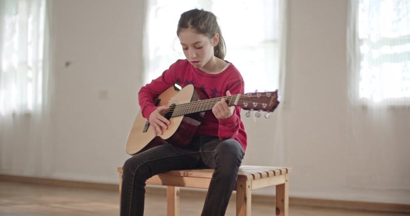 girl sitting and playing guitar