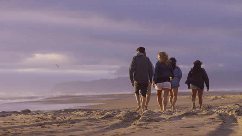 group of people walking on the beach on a cloudy day