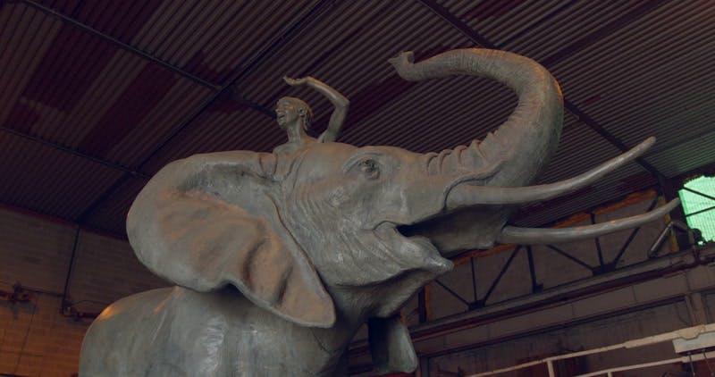 sculpture of a person on an elephants back on display indoors