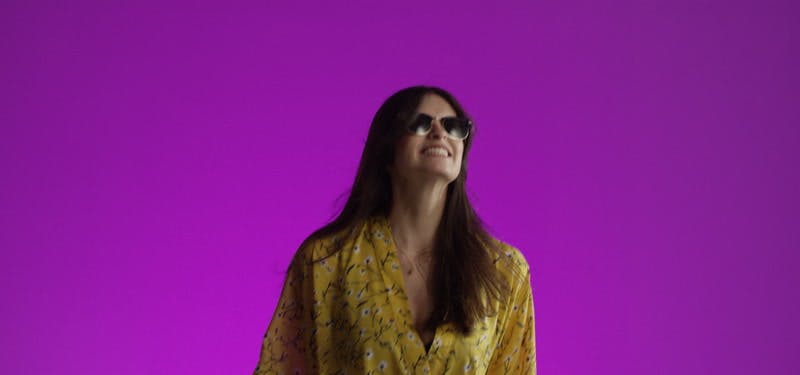 happy model jumping with sunglasses in purple background