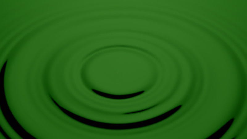 drop of water falling onto green liquid