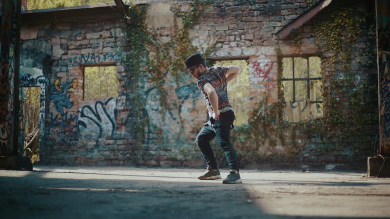 man dancing in abandoned building with graffiti on wall