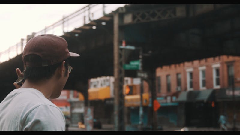 man listening to music on cellphone then looking straight at camera in city
