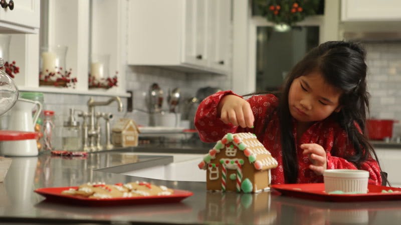 little girl decorating a gingerbread house