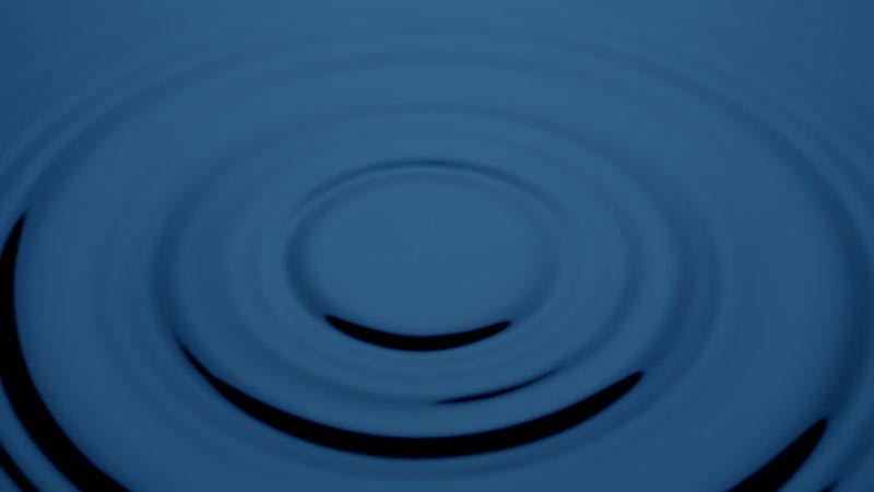drops of water falling onto blue liquid