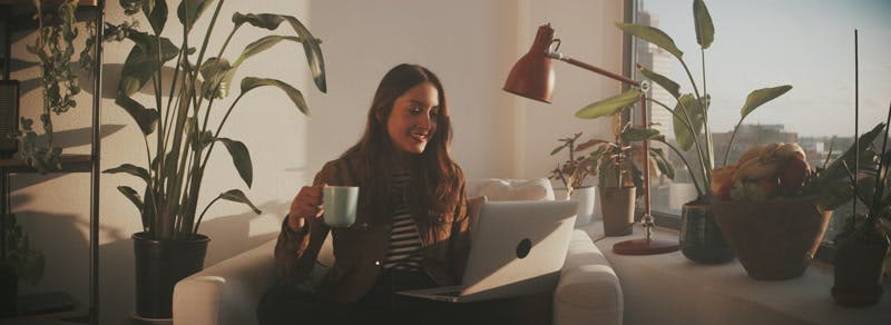 woman drinking coffee and showing someone her apartment on a video call