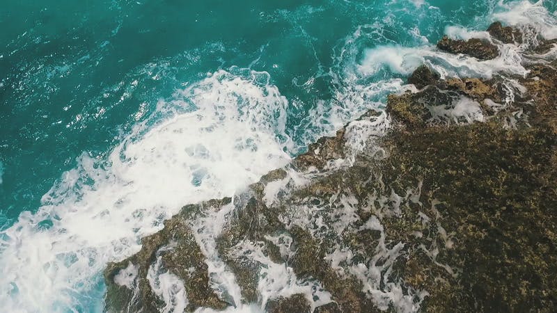 Large waves breaking on the side of a cliff aerial