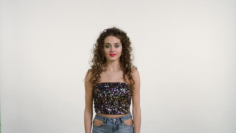 model standing while colorful balls are thrown at her white background