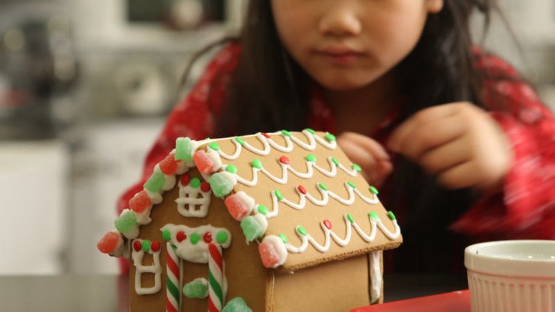 little girl carefully decorating a gingerbread house 
