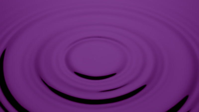 drop of water falling onto purple liquid