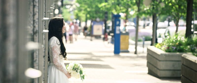 bride and groom standing on the sidewalk together and smiling at each other