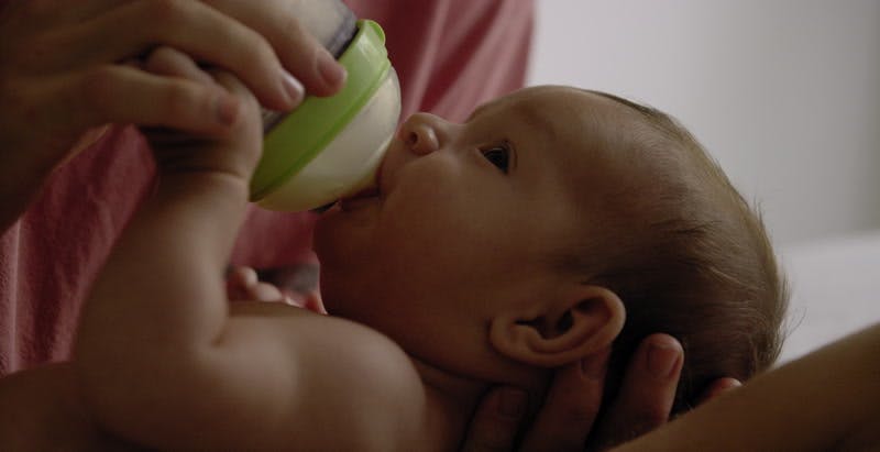 father holds and feeds baby milk with bottle