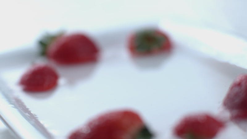 strawberry falling into a white dish with water 