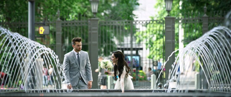bride and groom standing next to a fountain and enjoying each others company 