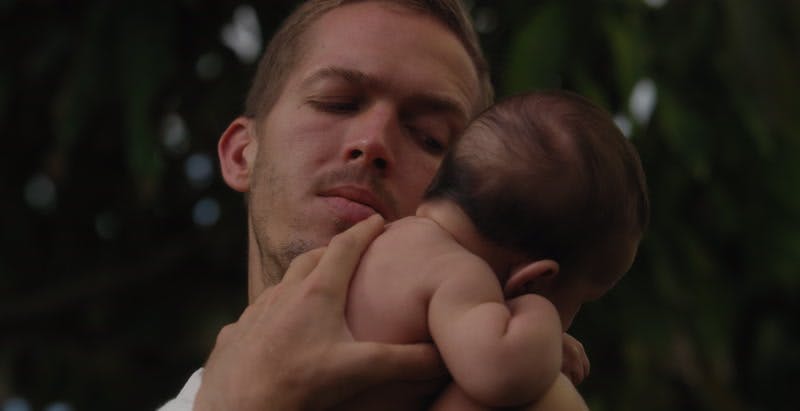 man looks at baby placed over shoulder and pats back gently