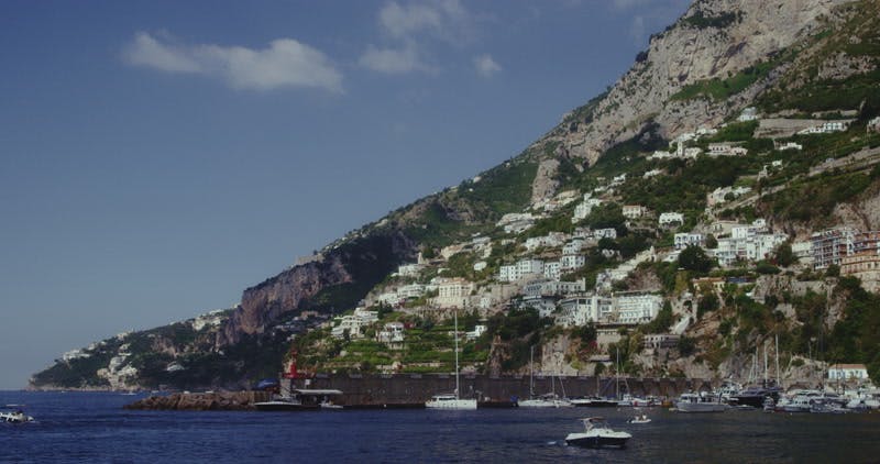 hillside village on the edge of the sea with boats and yachts sailing in the sea
