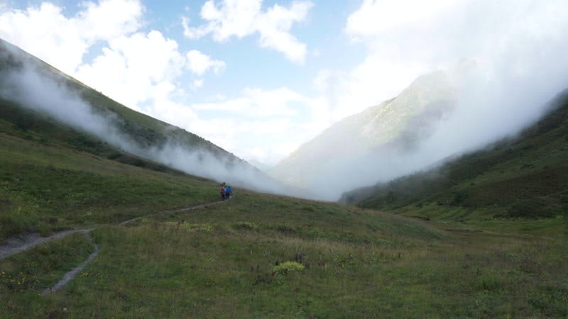 people walking on a trail in the cloudy mountains 