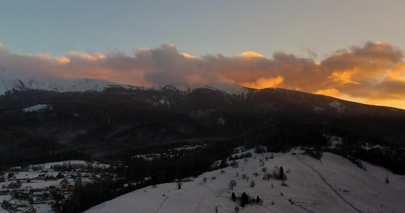 sunrise over a snowy mountain aerial