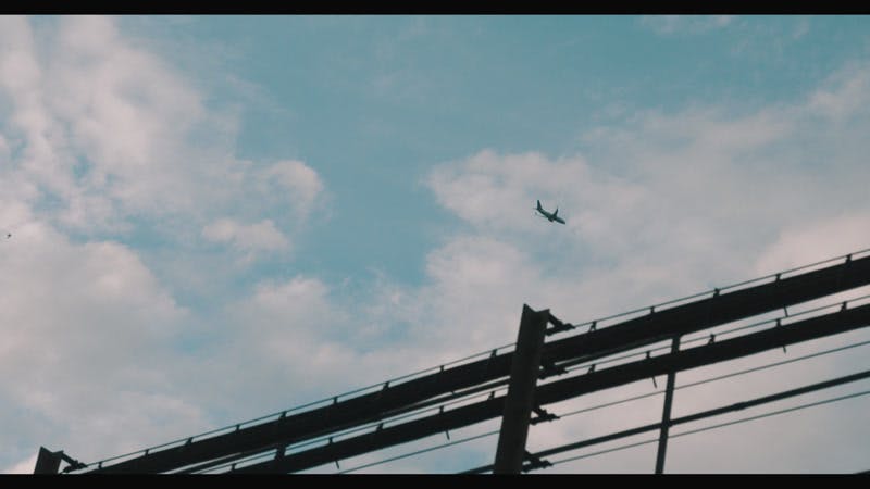 airplane flying over city seen from under train rail