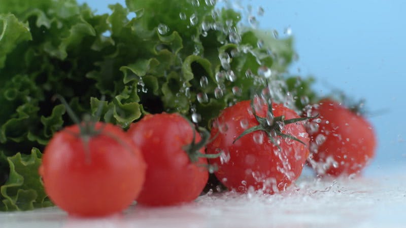 water falling on fresh lettuce and cherry tomatoes 
