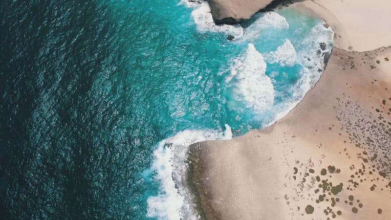 blue waves breaking over the beach aerial