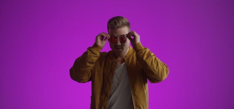 male model posing with trendy sunglasses in front purple background
