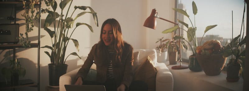 woman sitting on the couch while having a video call on her laptop 